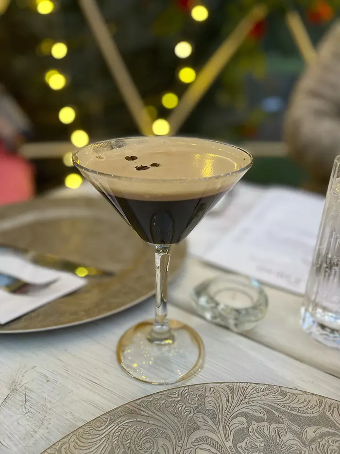 An espresso martini on a pod table under the lights
