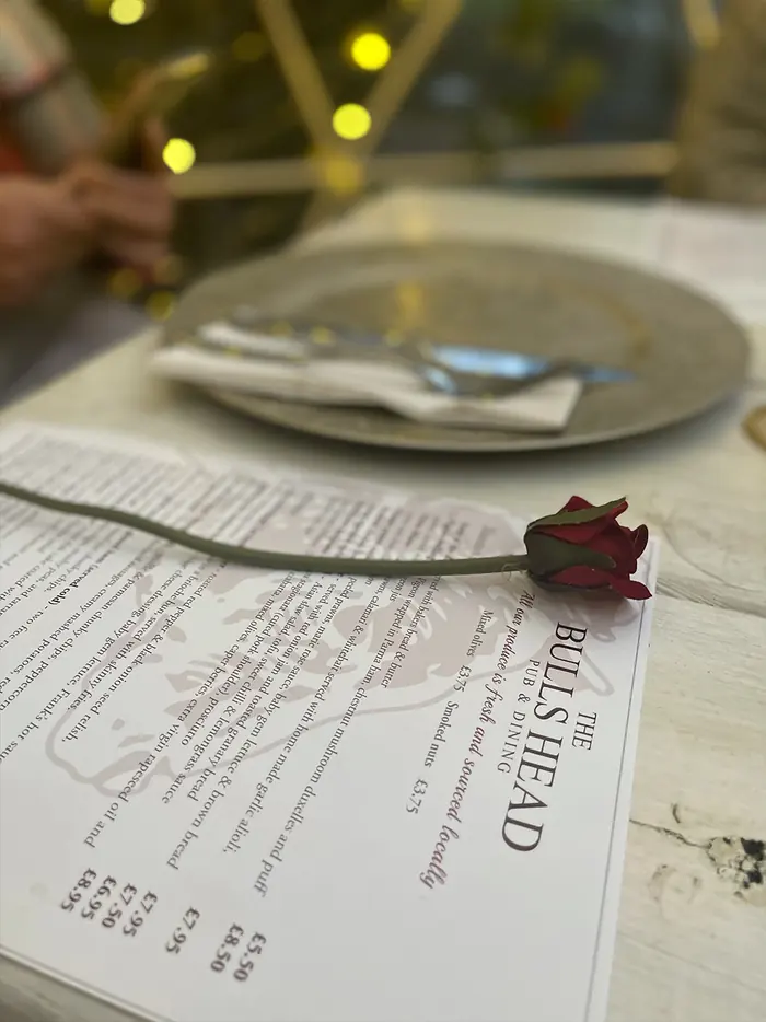A menu on a laid table at a pod, lights overhead