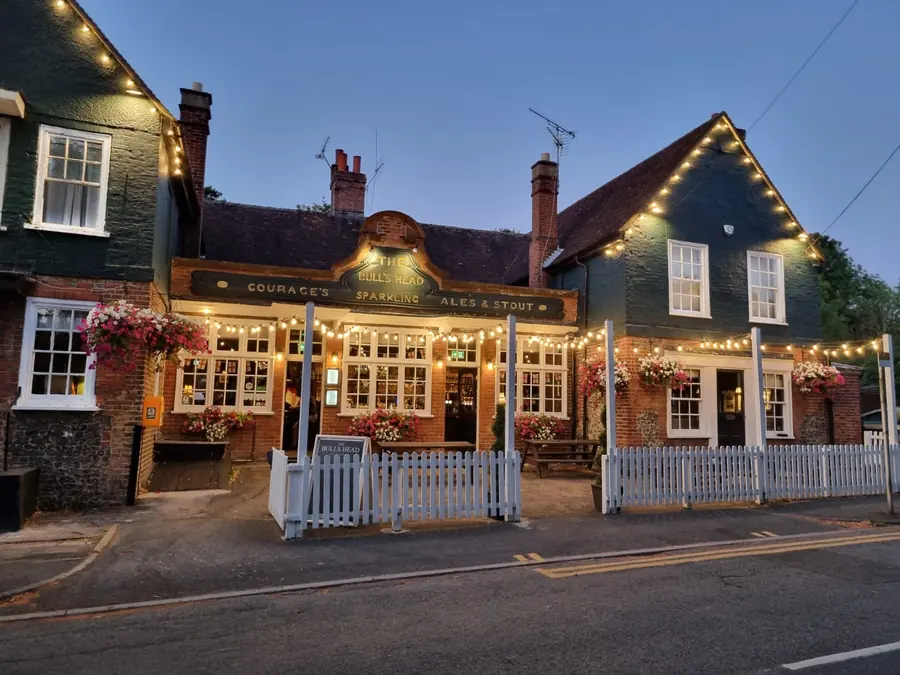 The front of The Bull's Head lit with festoon lights on a summer evening